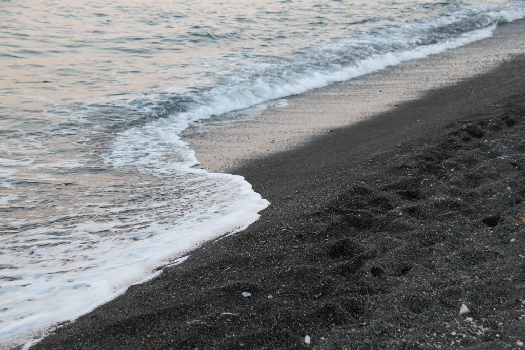 Praia Perissa em Santorini na Grécia. Praia de areia preta